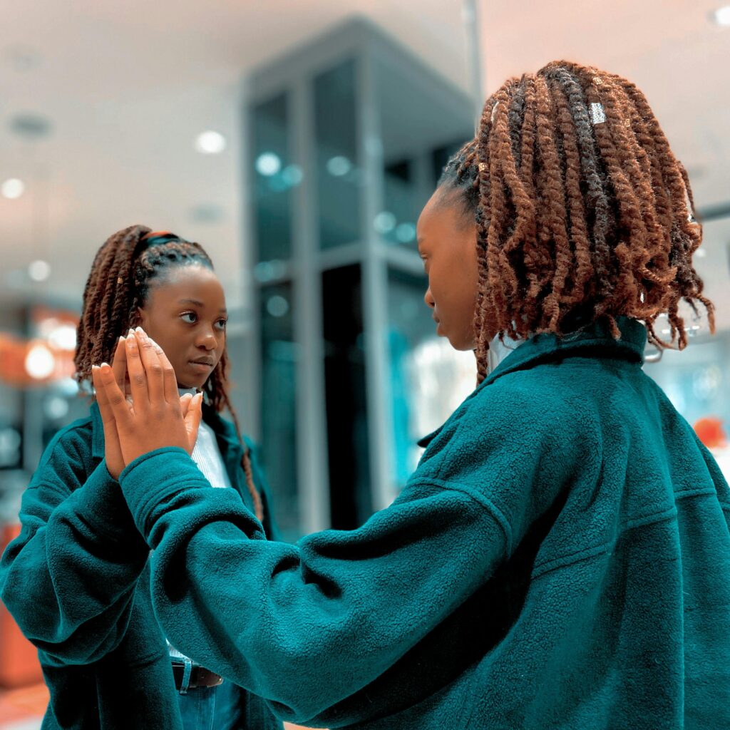 Captivating image of a young woman looking at her reflection in a mirror indoors.